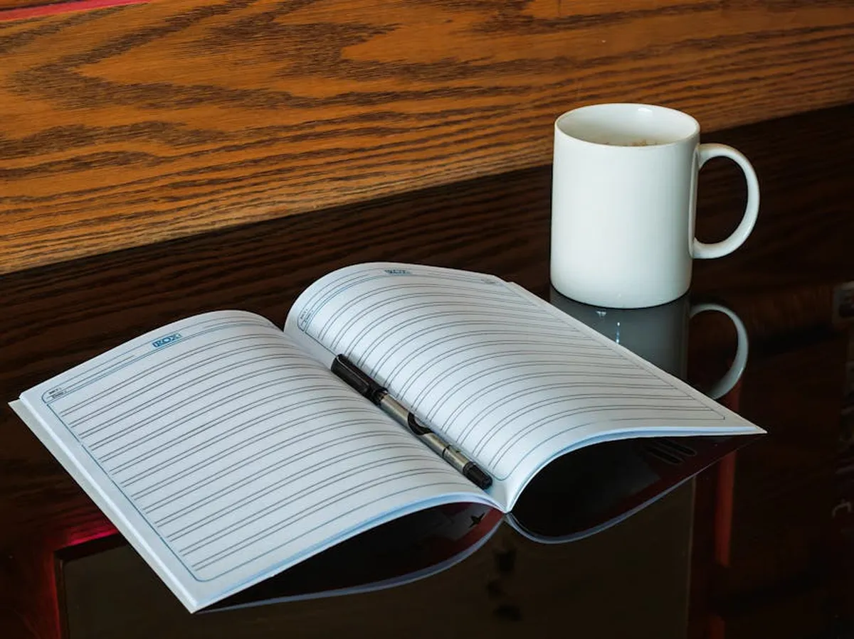 Caderno aberto com anotações manuscritas sobre uma mesa com café