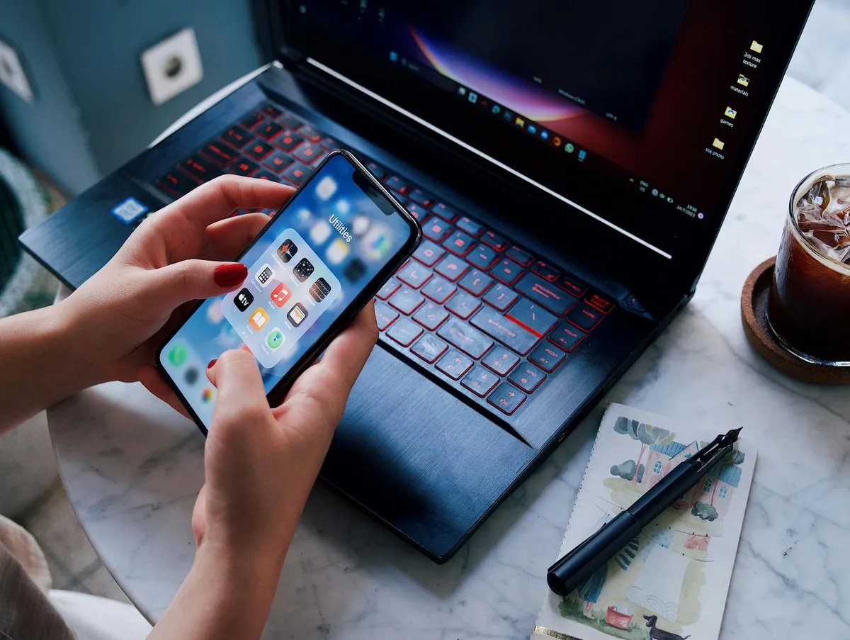 Smartphone e notebook abertos sobre mesa de estudos com caderno e caneta