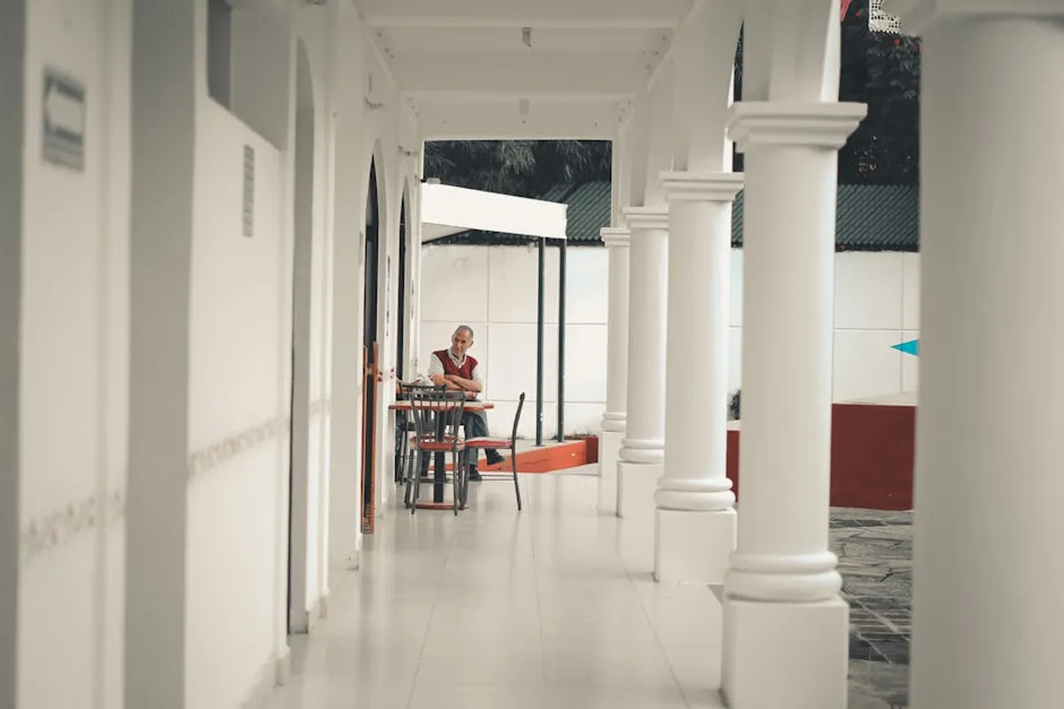 Pessoa sentada pensativa em corredor universitário com expressão preocupada