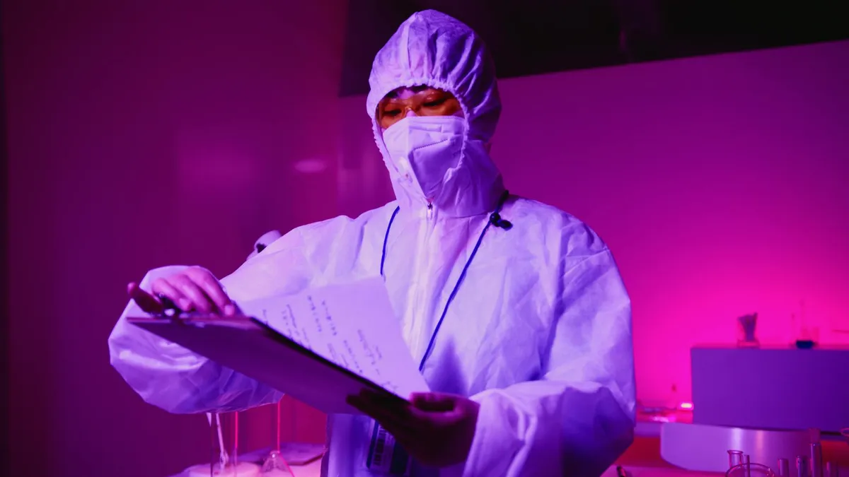 Pesquisador em laboratório consultando documentos de financiamento de pesquisa