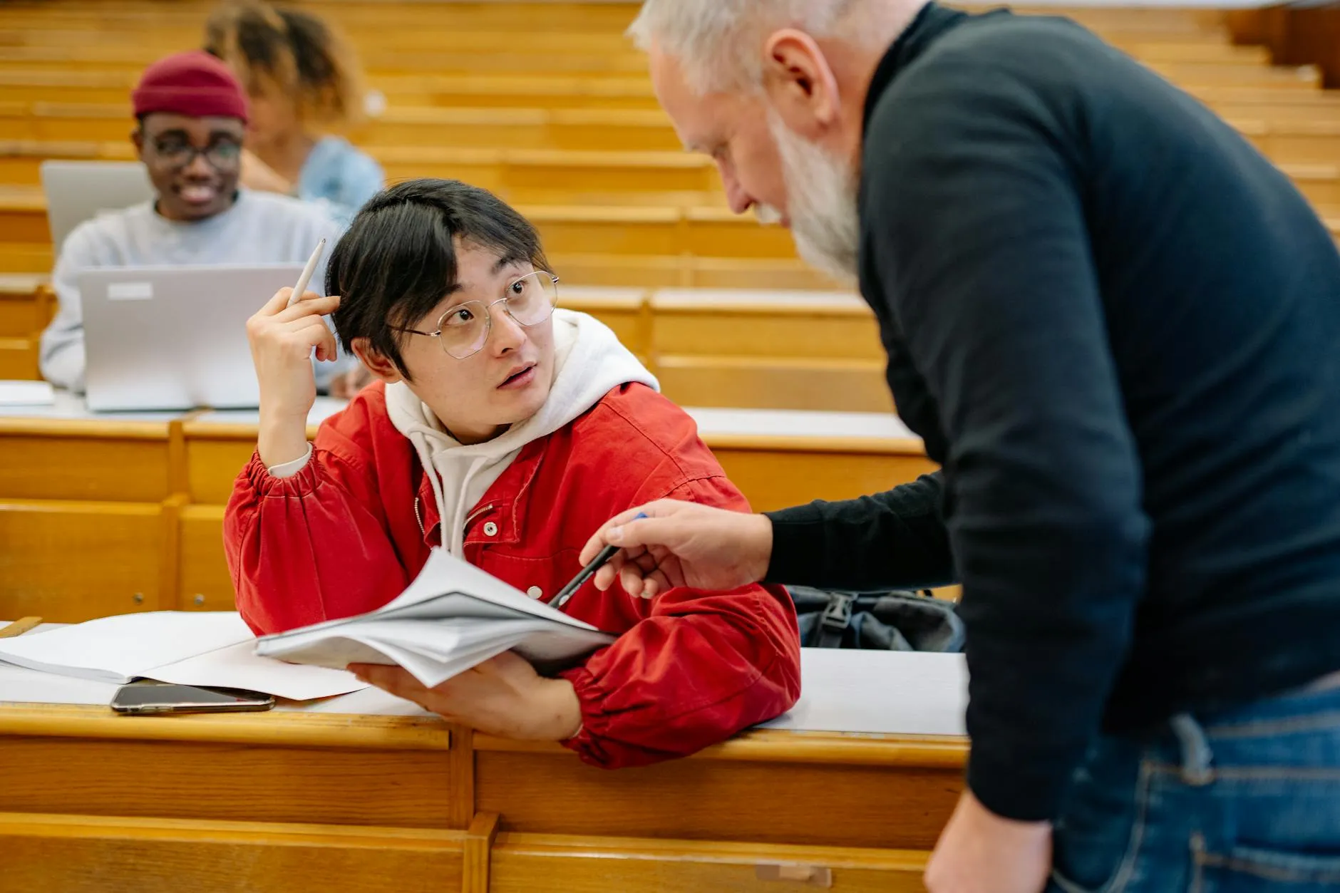 Professora assinando documento em mesa acadêmica com papéis e livros ao redor