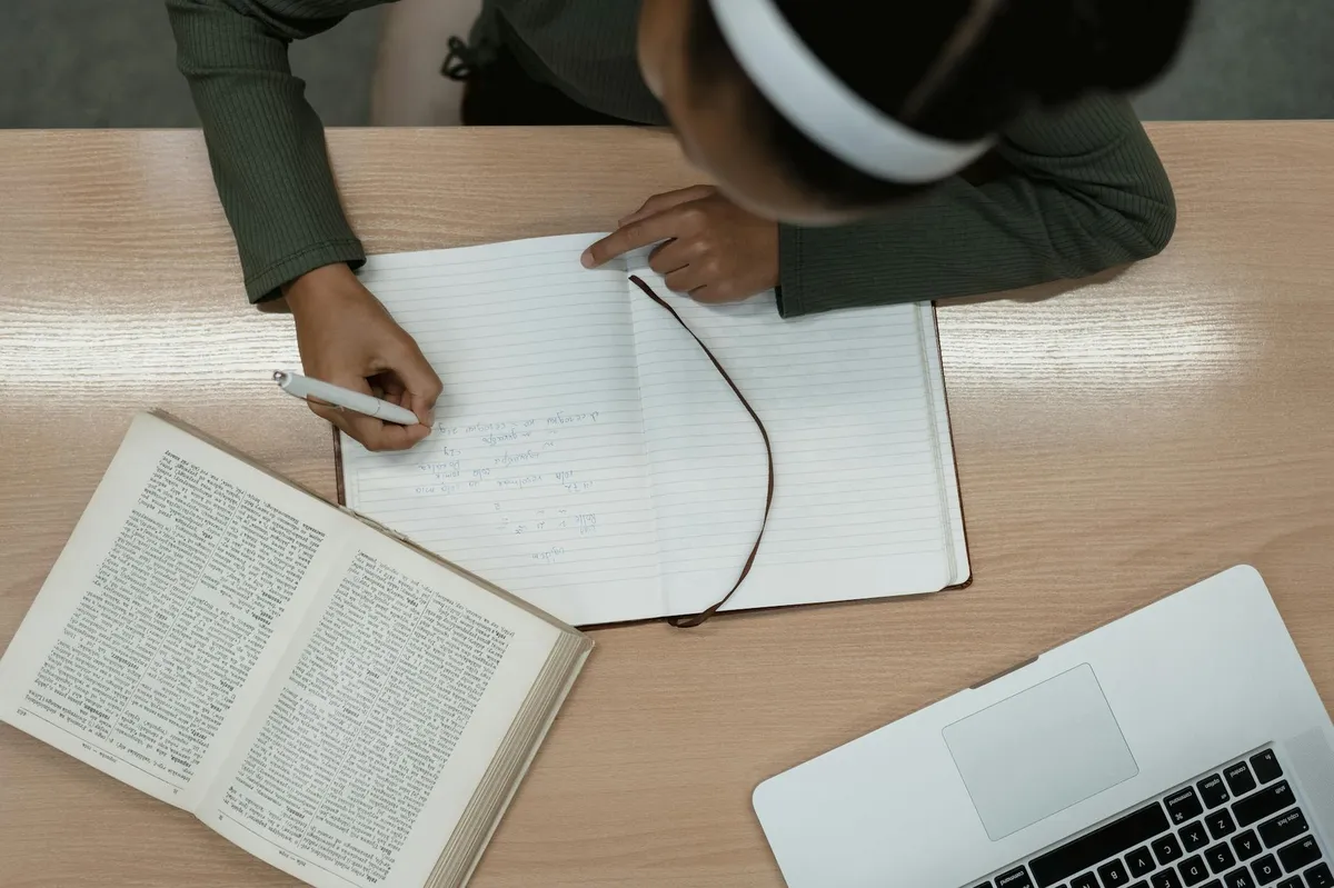 Pessoa estudando normas de citação com livros e caderno sobre a mesa