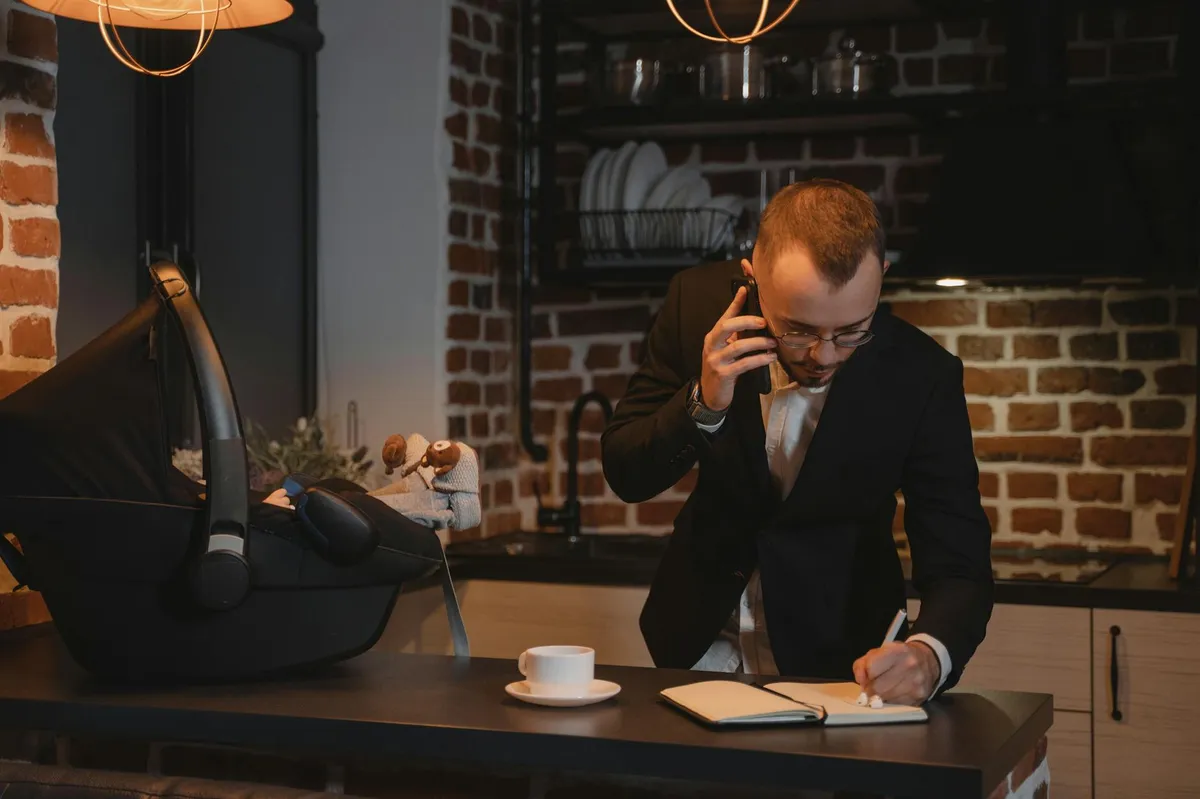 Pessoa equilibrando estudos, trabalho e vida familiar, com livros, computador e família ao fundo