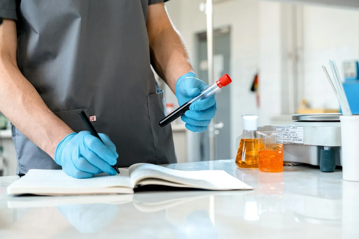 Pesquisadora escrevendo seção de metodologia de artigo em caderno de pesquisa