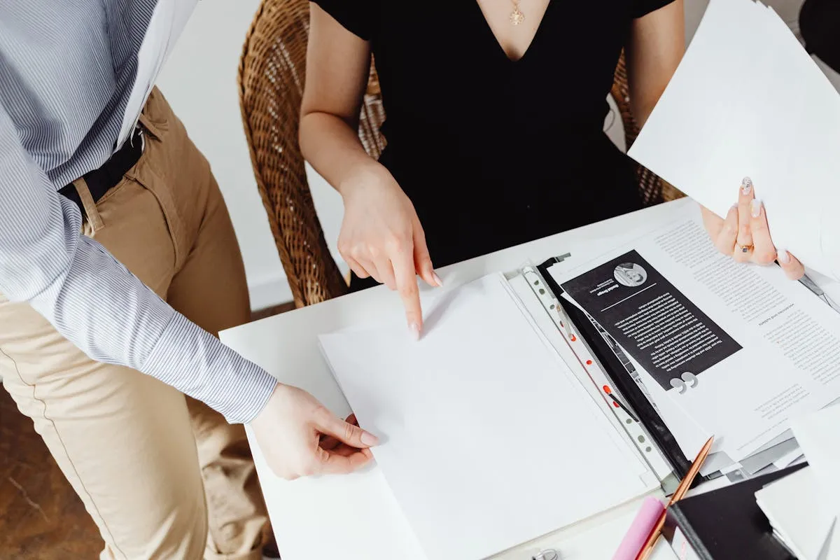 Dois pesquisadores colaborando na escrita de artigo científico com documentos e computador