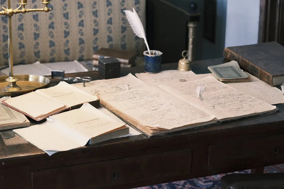 Pessoa escrevendo em notebook com documentos acadêmicos ao redor em mesa de trabalho