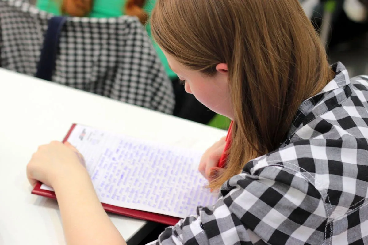 Estudante iniciante com caderno e caneta aprendendo formatação acadêmica