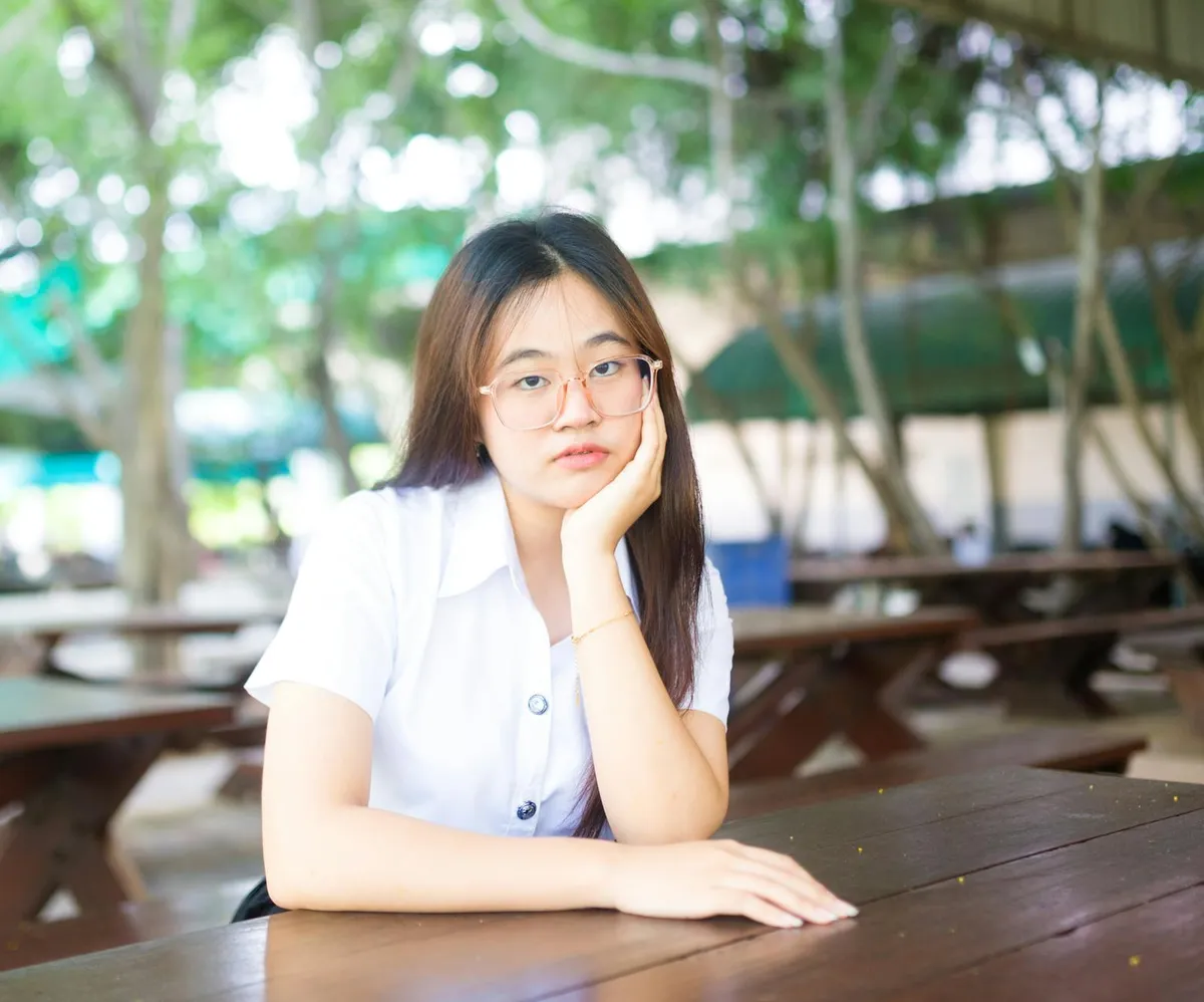 Estudante refletindo sobre decisão acadêmica com documentos universitários na mesa