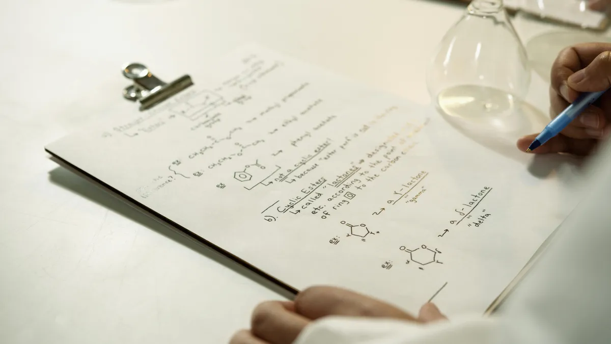 Pesquisadora organizando fichas e notas em mesa de trabalho com cadernos de campo