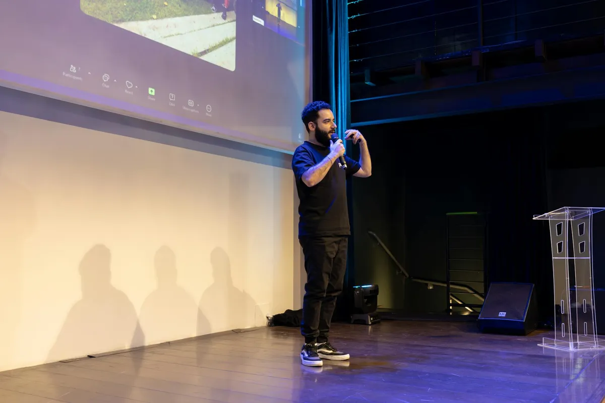 Pessoa apresentando em congresso científico com slides ao fundo