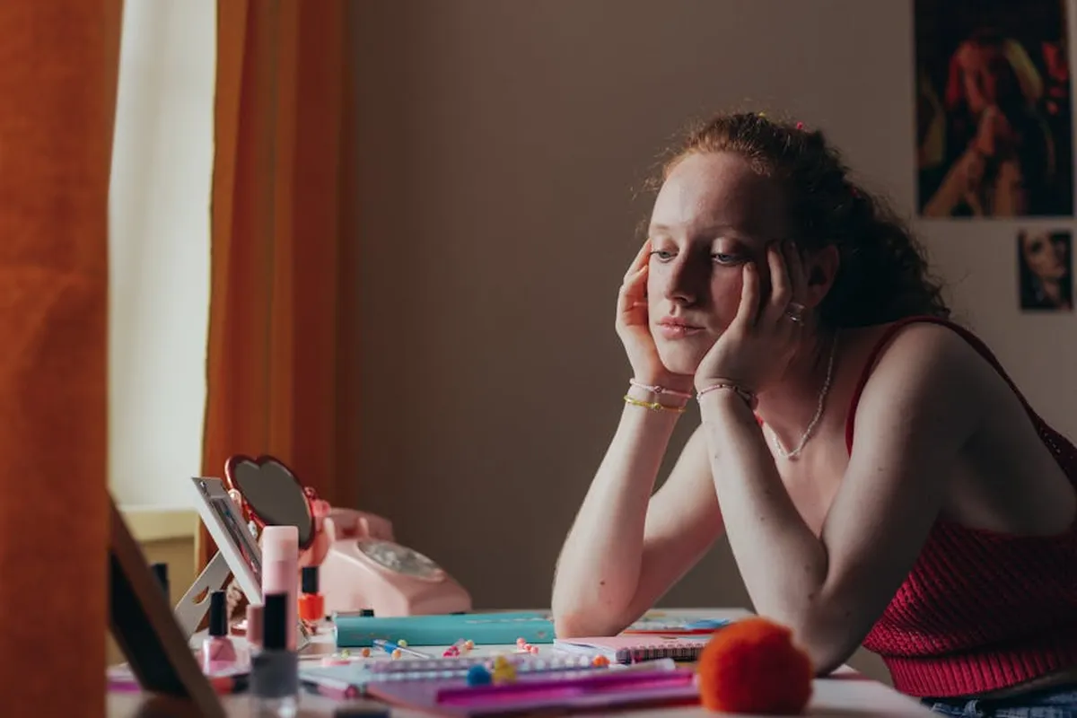 Pessoa sentada sozinha em mesa de trabalho com expressão pensativa