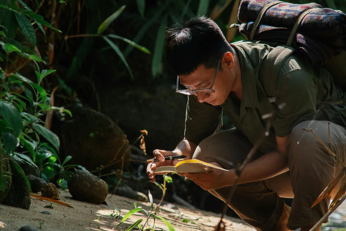 Pesquisador fazendo anotações em caderno durante observação em campo
