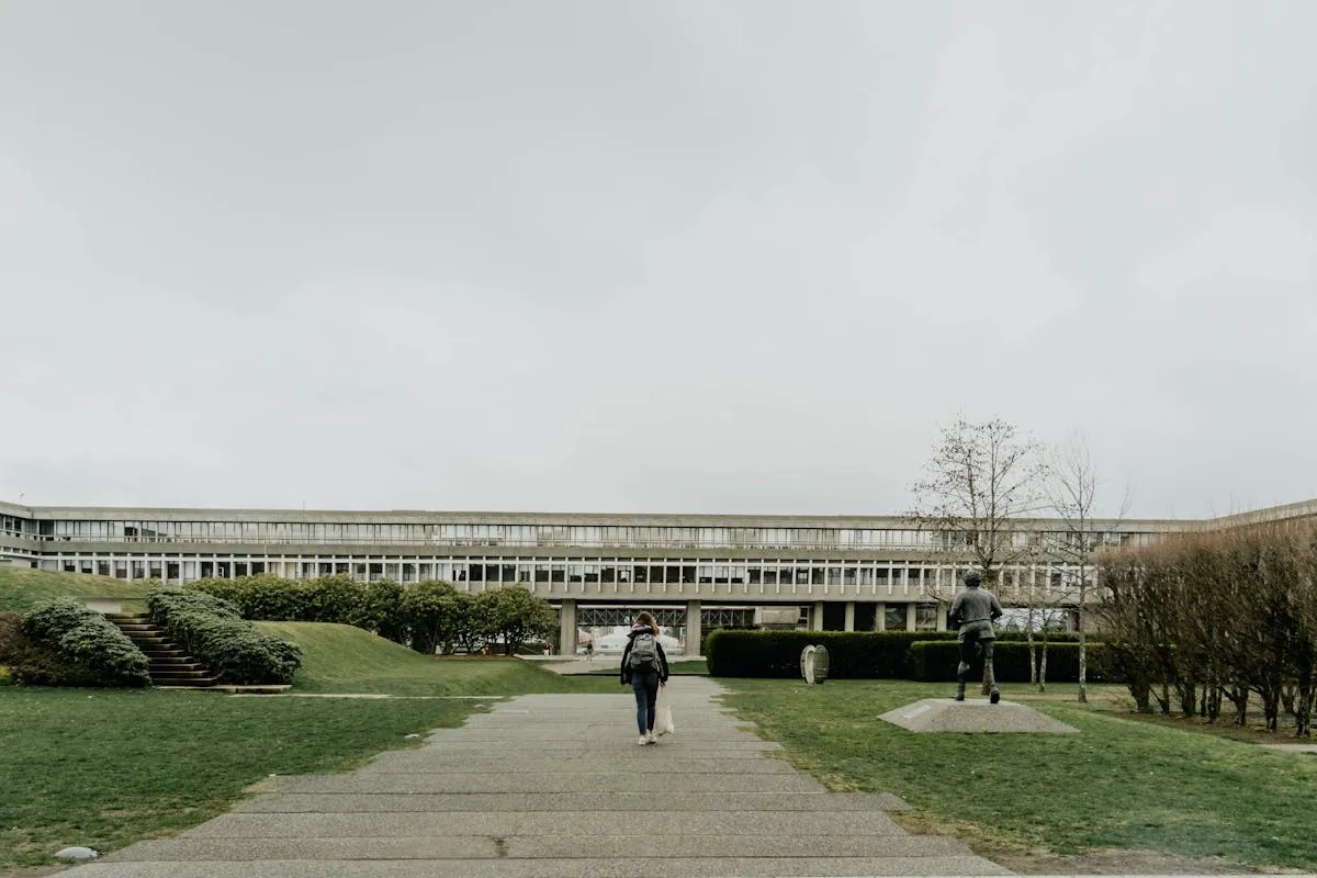 Pesquisadora com mala em frente a universidade no exterior em dia ensolarado