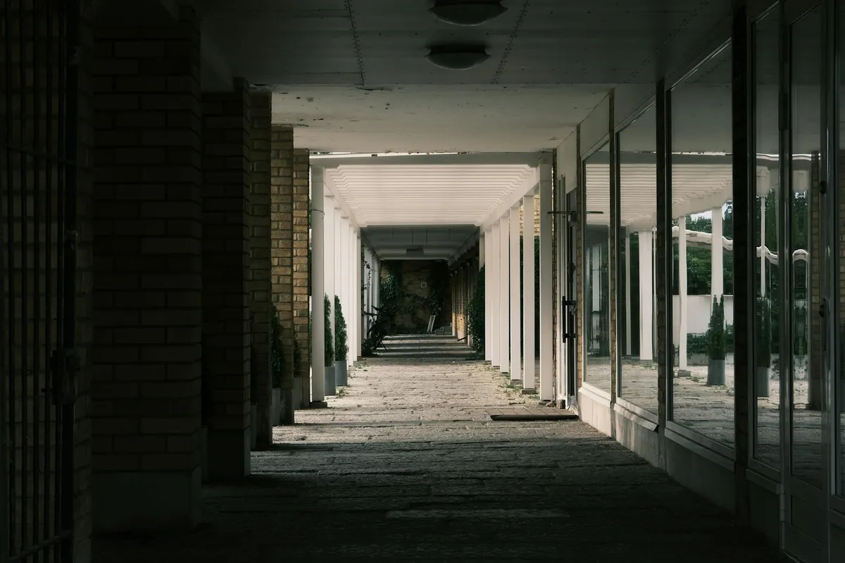 Professor universitário em corredor de universidade, em momento de reflexão