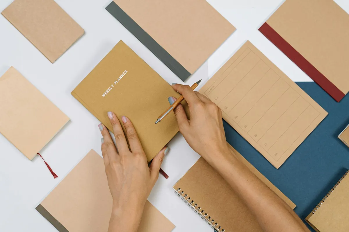 Pesquisador organizando tarefas em caderno e aplicativo, com café ao lado