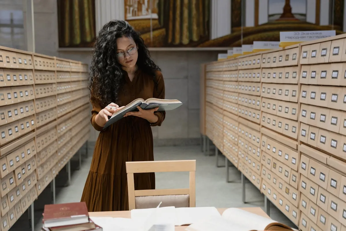 Pesquisadora lendo guia metodológico em biblioteca com livros ao fundo