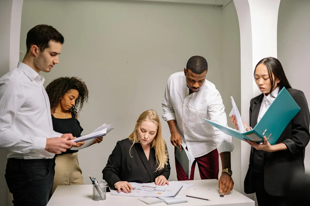 Pessoas em reunião de trabalho com notebooks e dados em tela