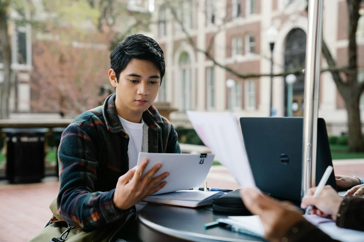 Estudante com livros e notebook, sobrecarregado de estudo em mesa acadêmica