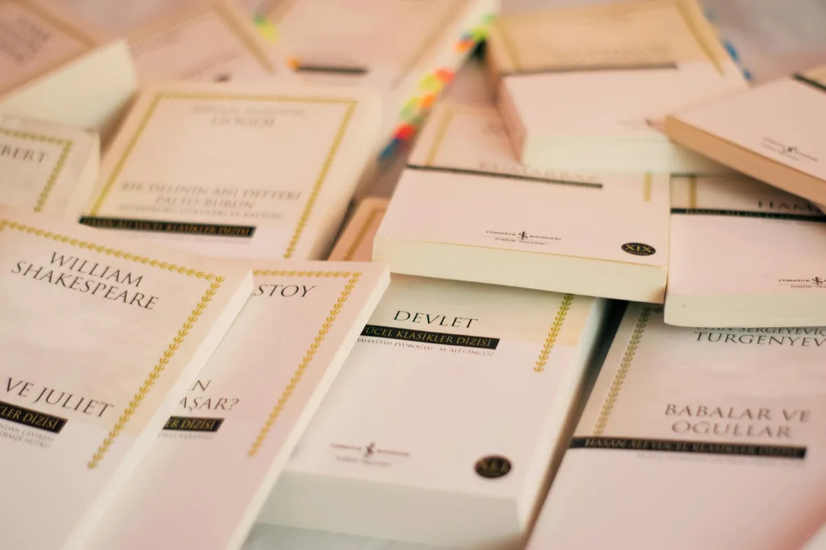 Biblioteca universitária com prateleiras de livros e mesa de estudos com materiais acadêmicos de literatura