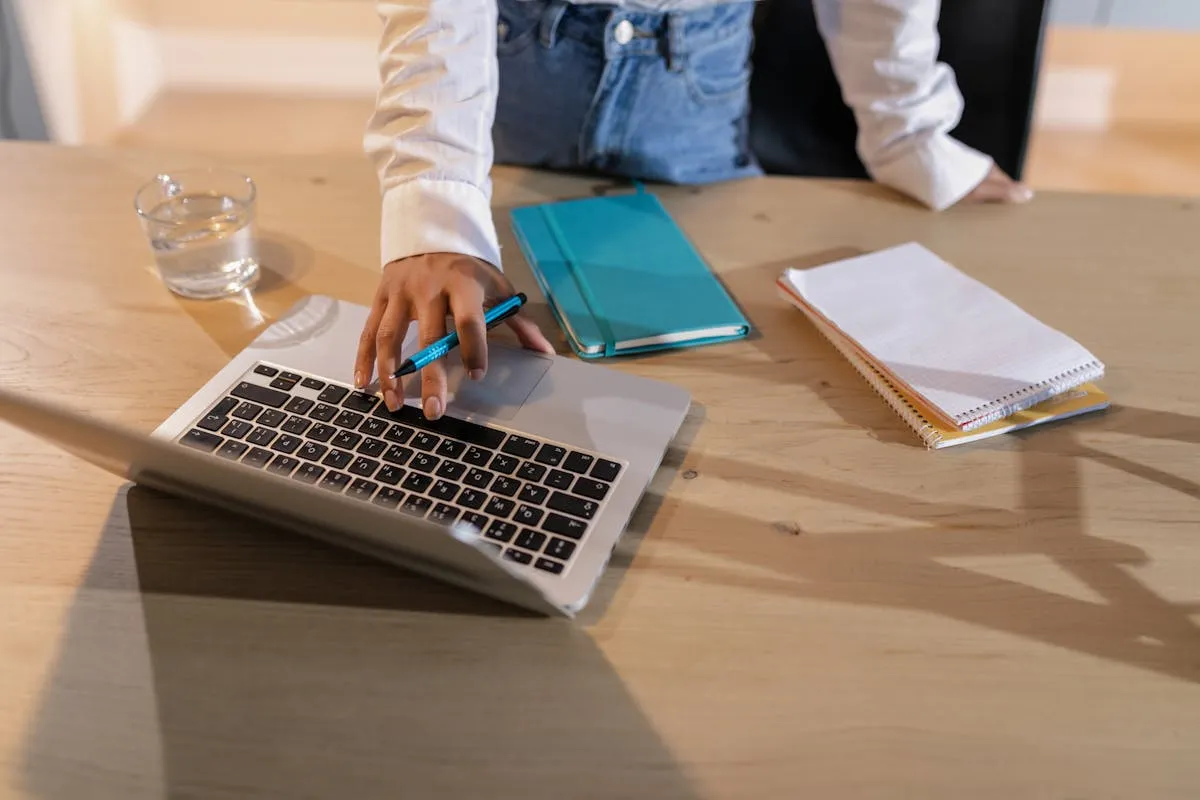 Profissional estudando em laptop durante horário de descanso no trabalho com caderno de anotações