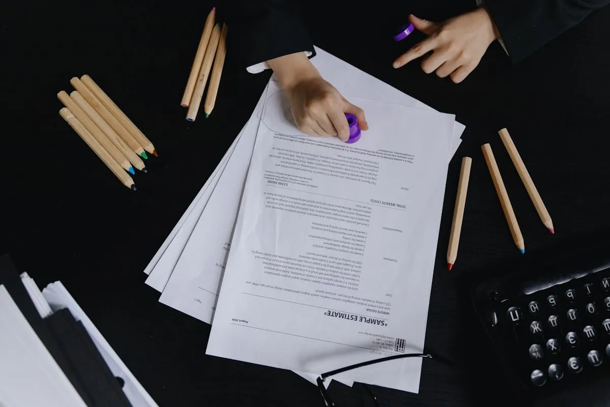 Documentos acadêmicos com marcações e caneta sobre mesa de estudo