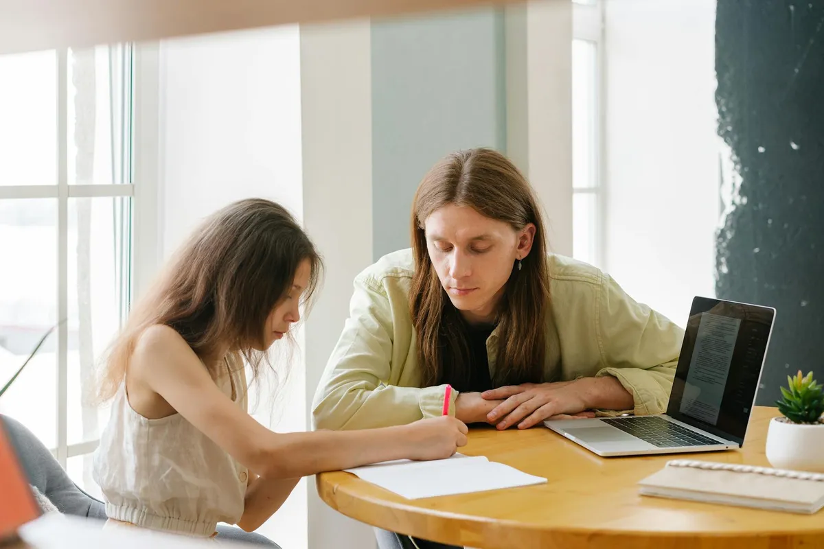 Pai pesquisador estudando em casa enquanto cuida do filho pequeno ao lado