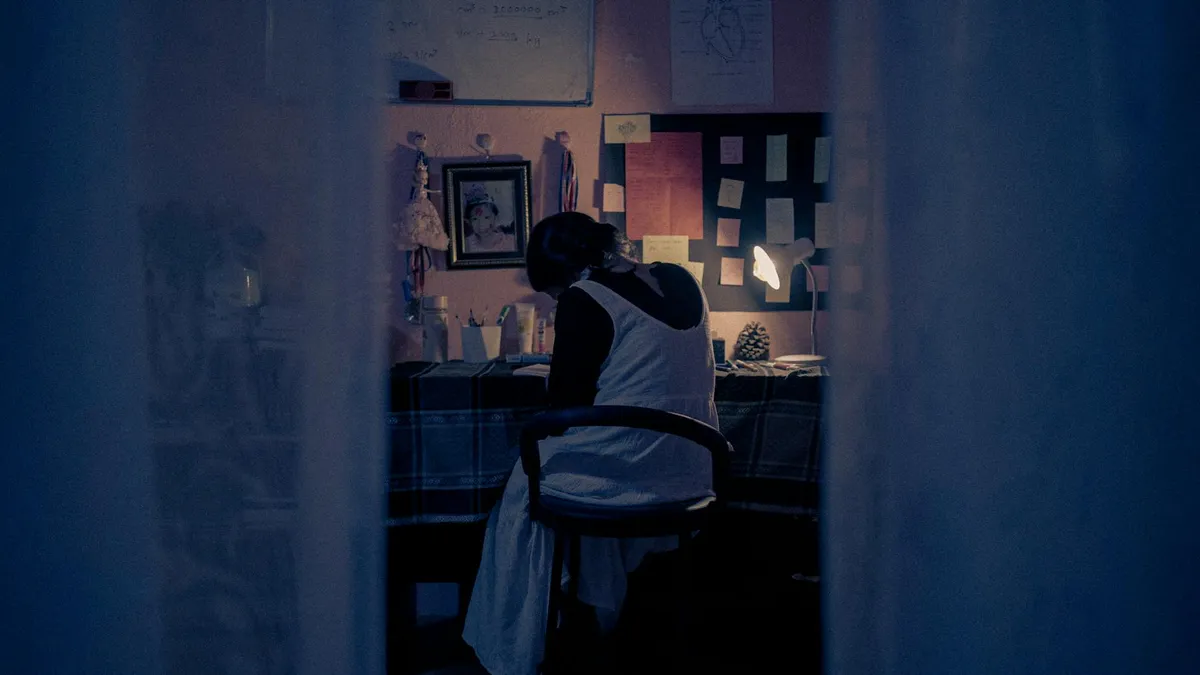 Pessoa estudando em casa com livros e computador, representando pesquisador independente