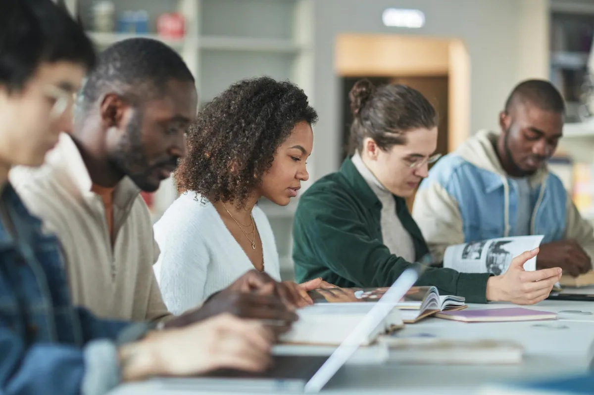 Estudante de pós-graduação trabalhando sozinha em biblioteca com expressão de cansaço