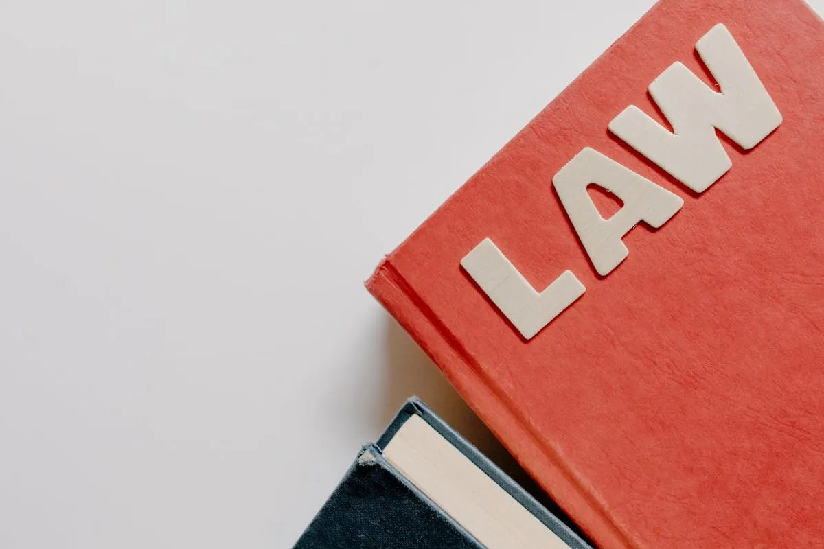 Estudante de direito com livros jurídicos e computador escrevendo projeto de pesquisa