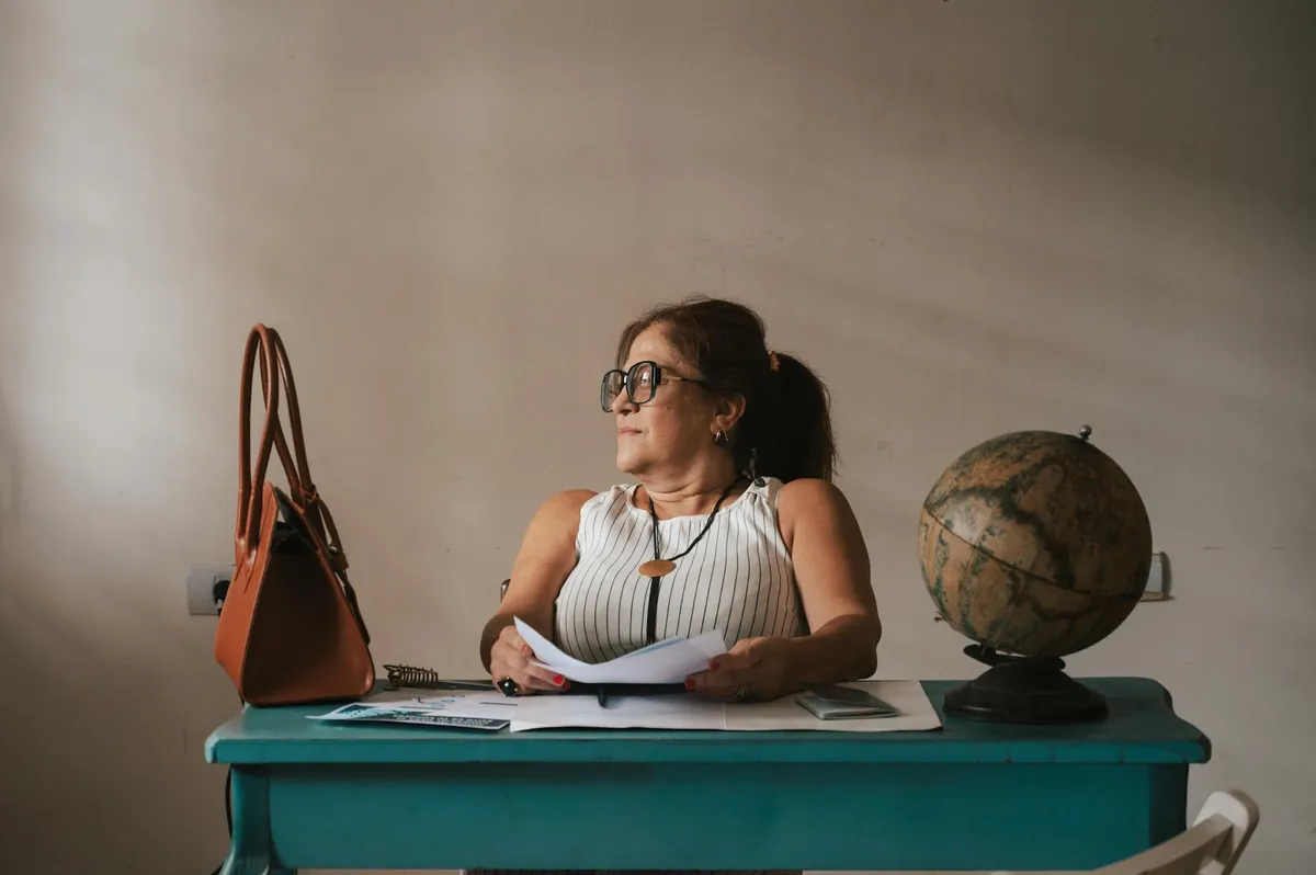 Professor com expressão cansada olhando para papéis sobre mesa