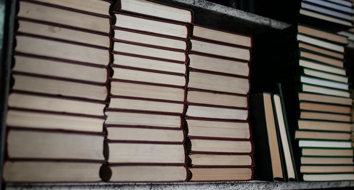 Livros acadêmicos empilhados em uma mesa de biblioteca