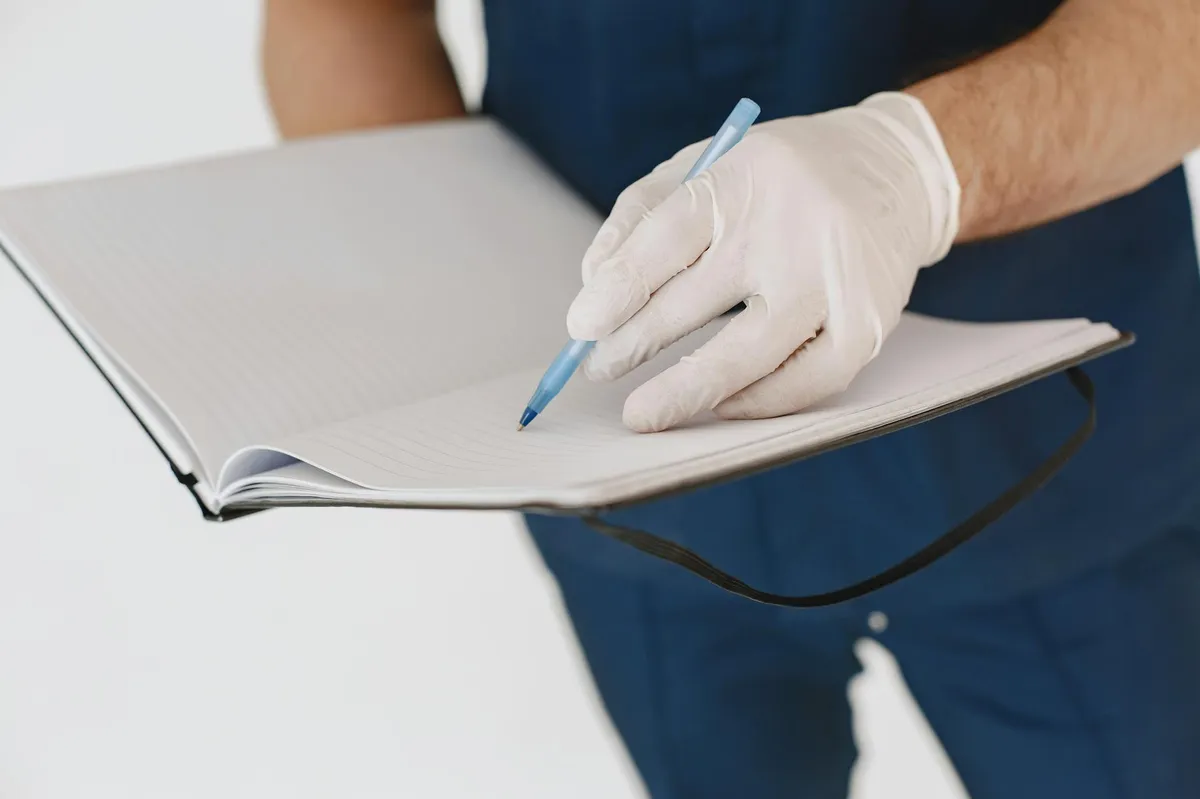 Enfermeira escrevendo relato de experiência clínica em mesa de trabalho