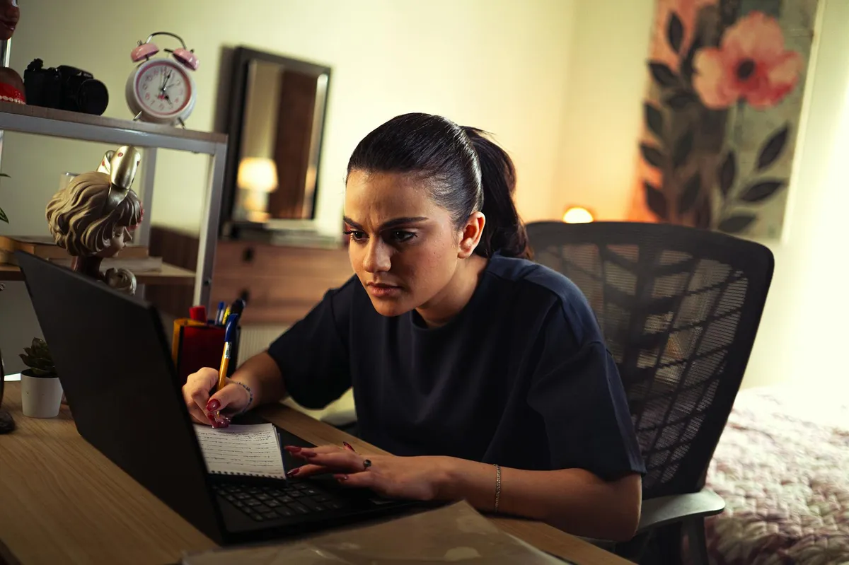 Pós-graduanda trabalhando no notebook em casa, equilibrando pesquisa e projetos paralelos