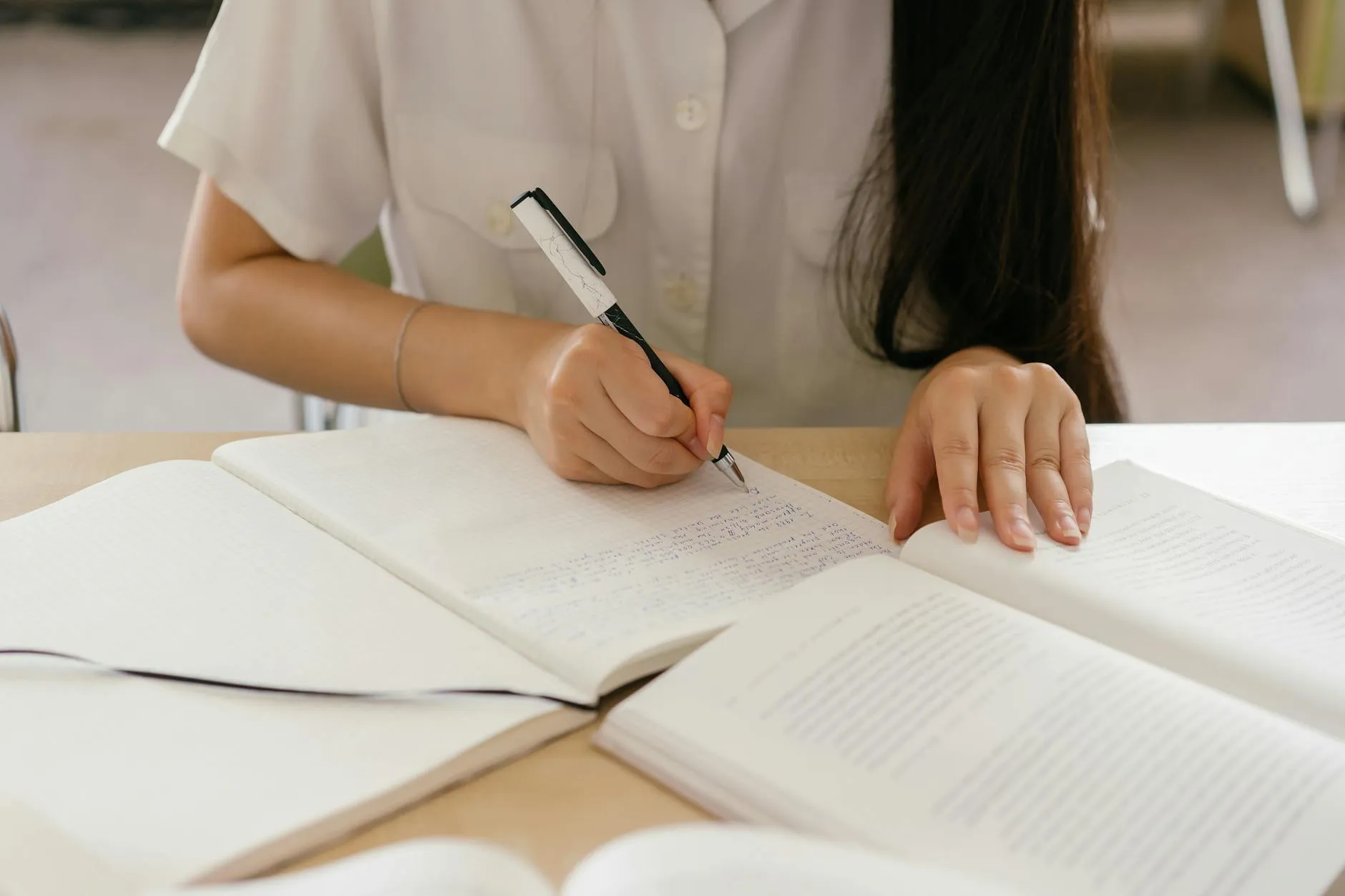 Pesquisadora revisando texto acadêmico em mesa com caderno e computador