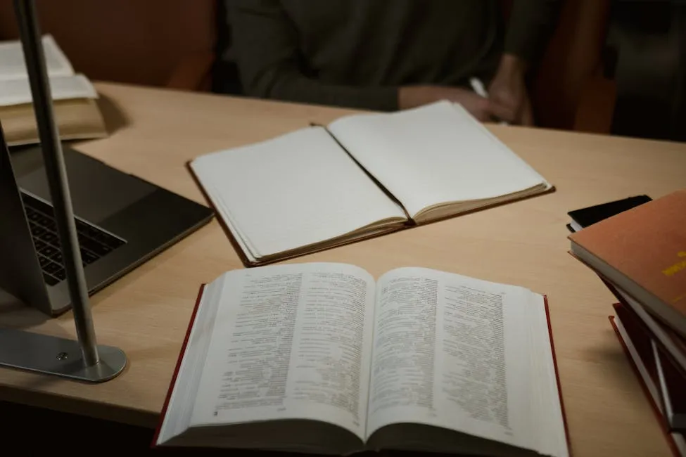 Pesquisadora escrevendo tese em mesa de trabalho com anotações e livros abertos