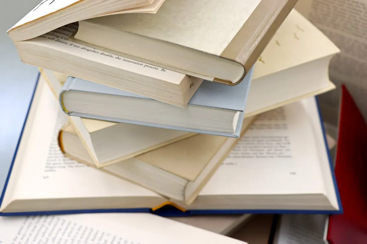 Pilha de trabalhos acadêmicos encadernados em mesa universitária