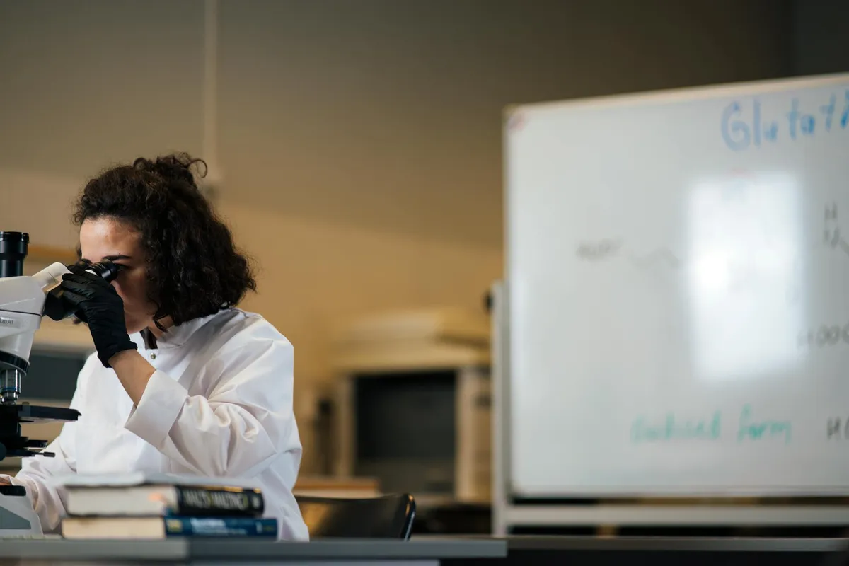 Pesquisadora examinando amostras ao microscópio em um laboratório