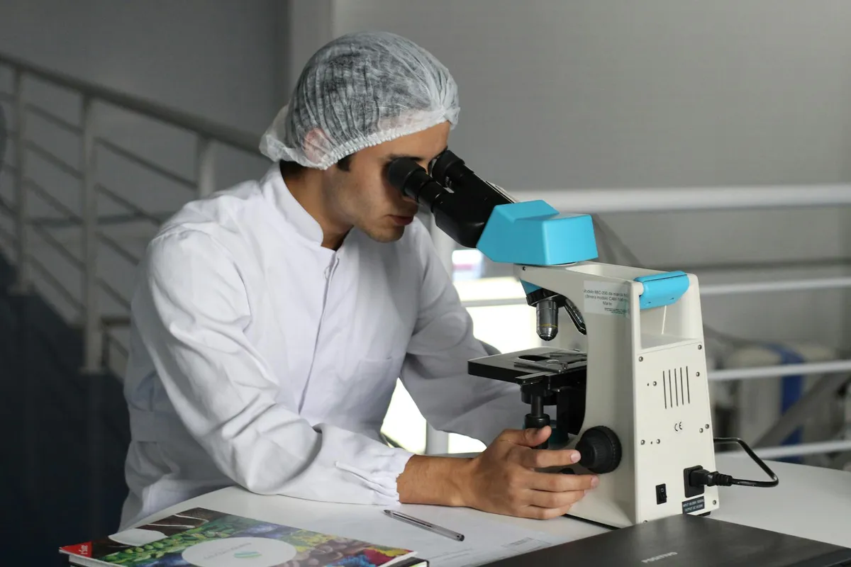 Pesquisador de jaleco usando microscópio em laboratório de pesquisa em saúde